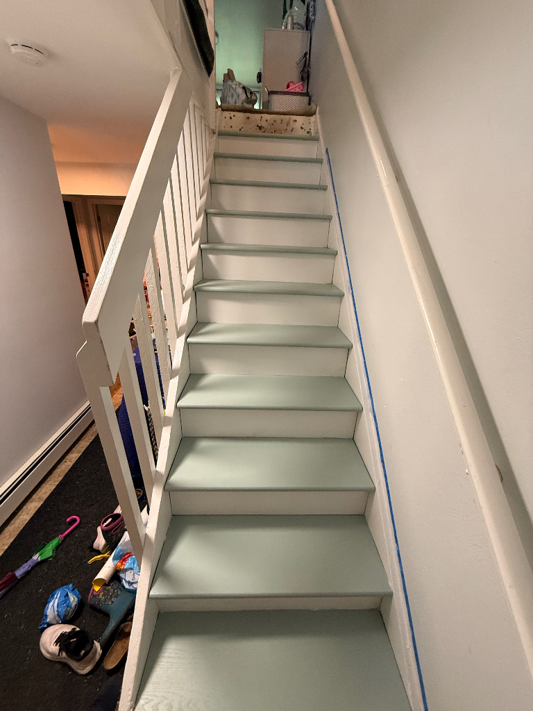 A freshly painted stairway, the rails and risers are white while the treads (steps) are a lite mintsish green. 