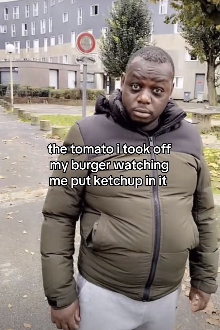 Photo of a man standing outside with a funny look on his face with the caption “the tomato i took off my burger watching me put ketchup in it”